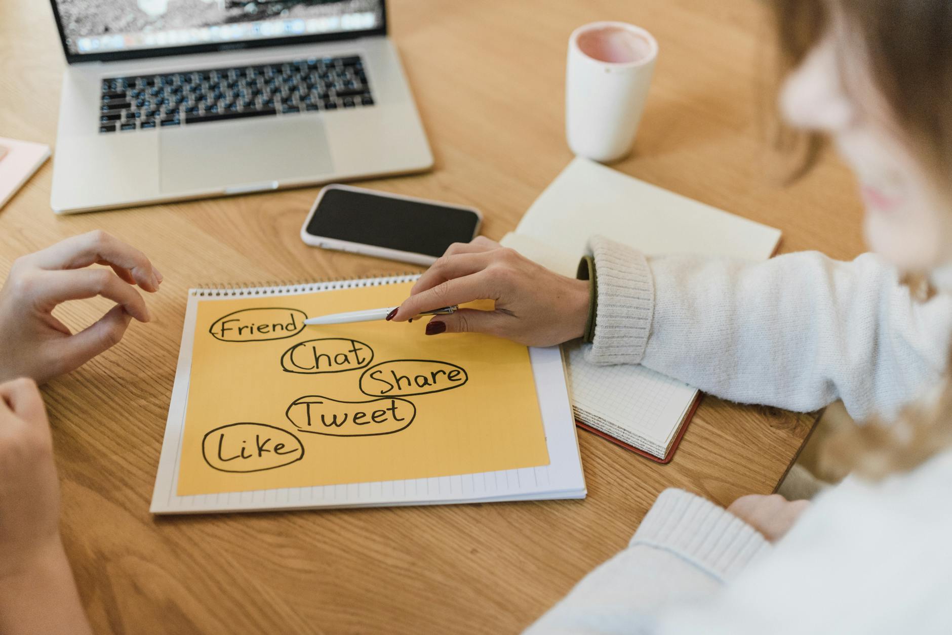 Dwie kobiety omawiają strategię online przy laptopie w biurze