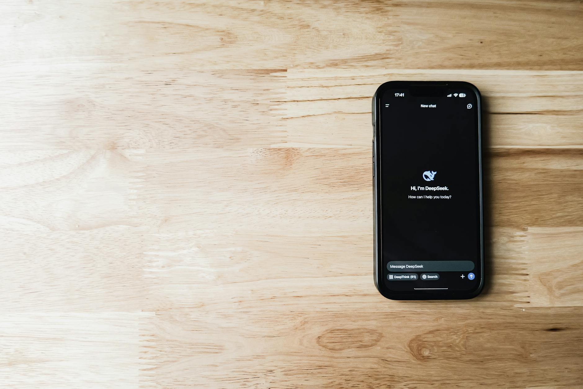 Smartfon z aplikacją asystenta AI leżący na jasnym drewnianym stole