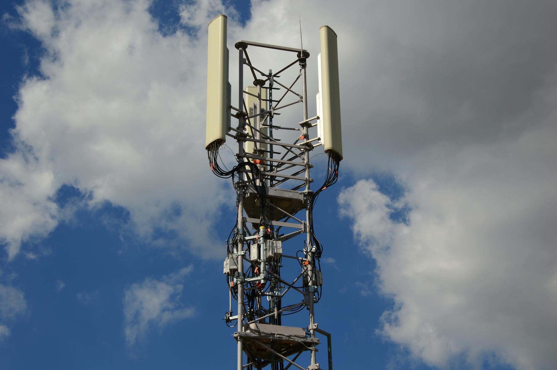 Nowoczesna wieża komórkowa 5G z antenami na tle nieba z chmurami