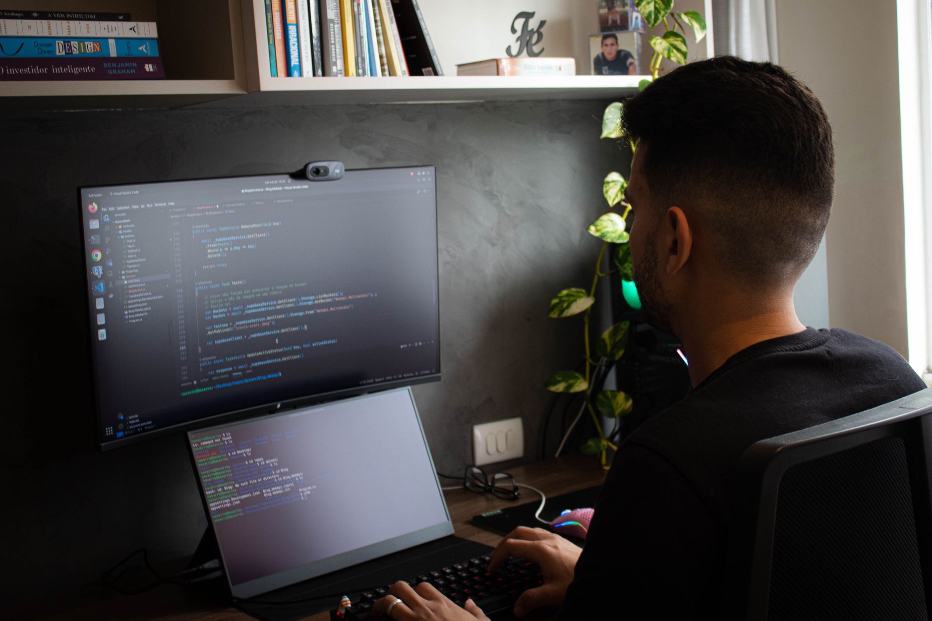 Programista przy biurku pracujący na laptopie i monitorze w nowoczesnym biurze Programista przy biurku pracujący na laptopie i monitorze w nowoczesnym biurze