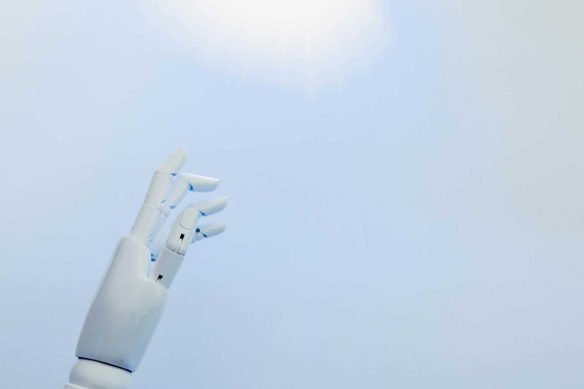 Nowe trendy w automatyzacji IT: od GitOps po AI Ops w codziennej pracy administratora Robotyczna dłoń sięga po jasne światło na białym tle