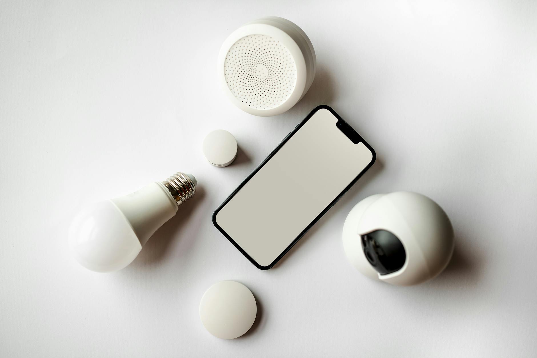 Inteligentny dom bez remontu: sprytne gadżety smart do każdego mieszkania Smartfon i gadżety smart home ułożone na białym tle