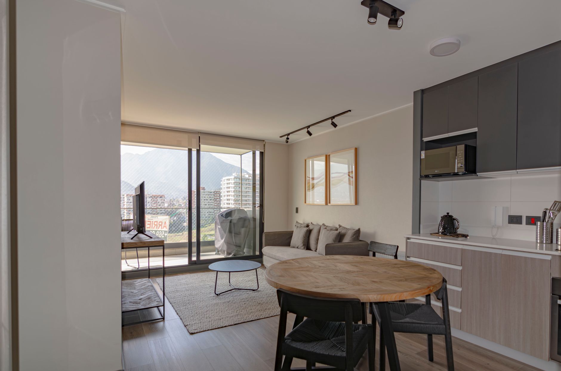 Jasny salon z aneksem kuchennym i wyjściem na balkon w małym mieszkaniu