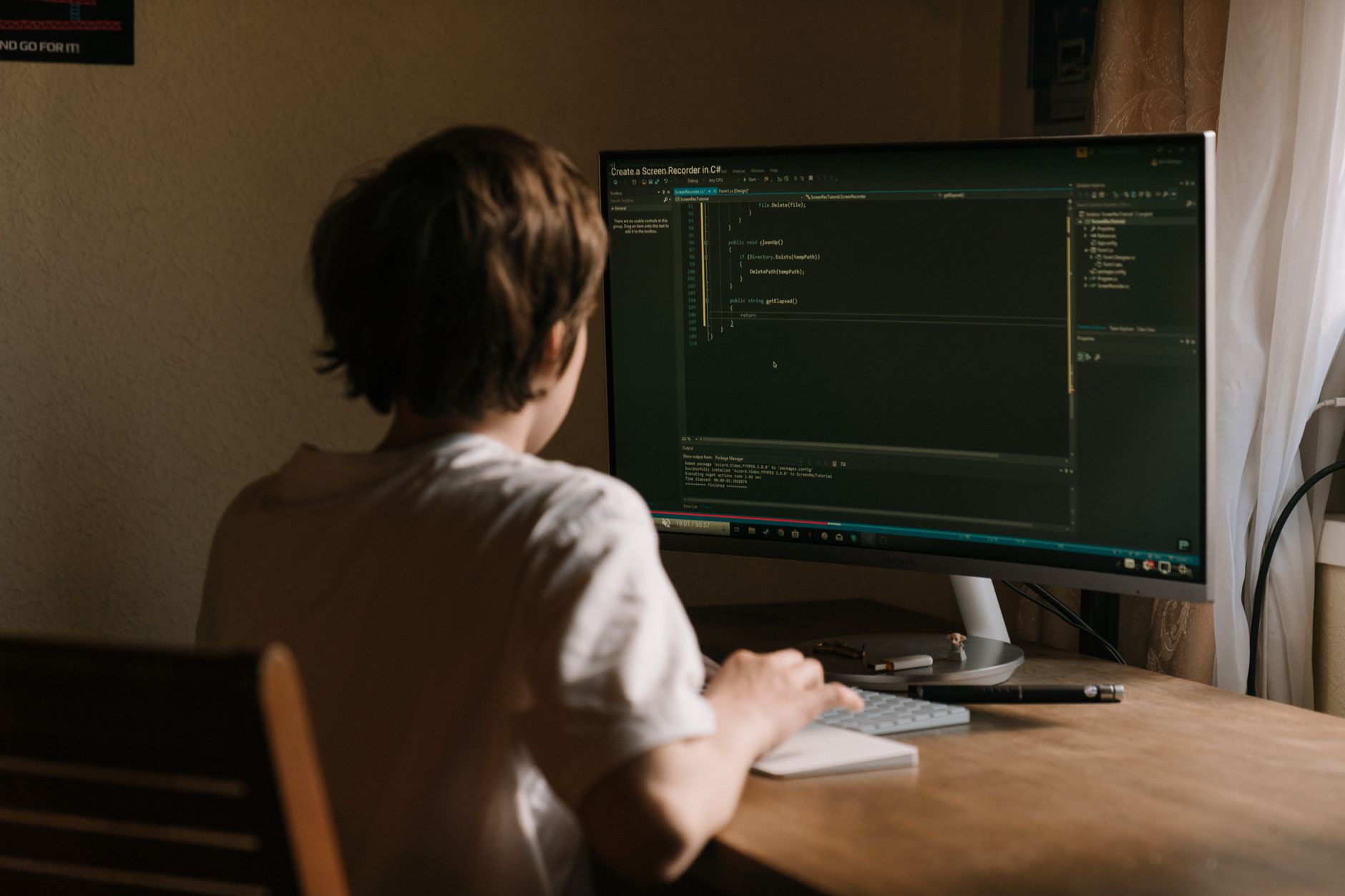 Nastolatek programuje na komputerze w domowym biurze