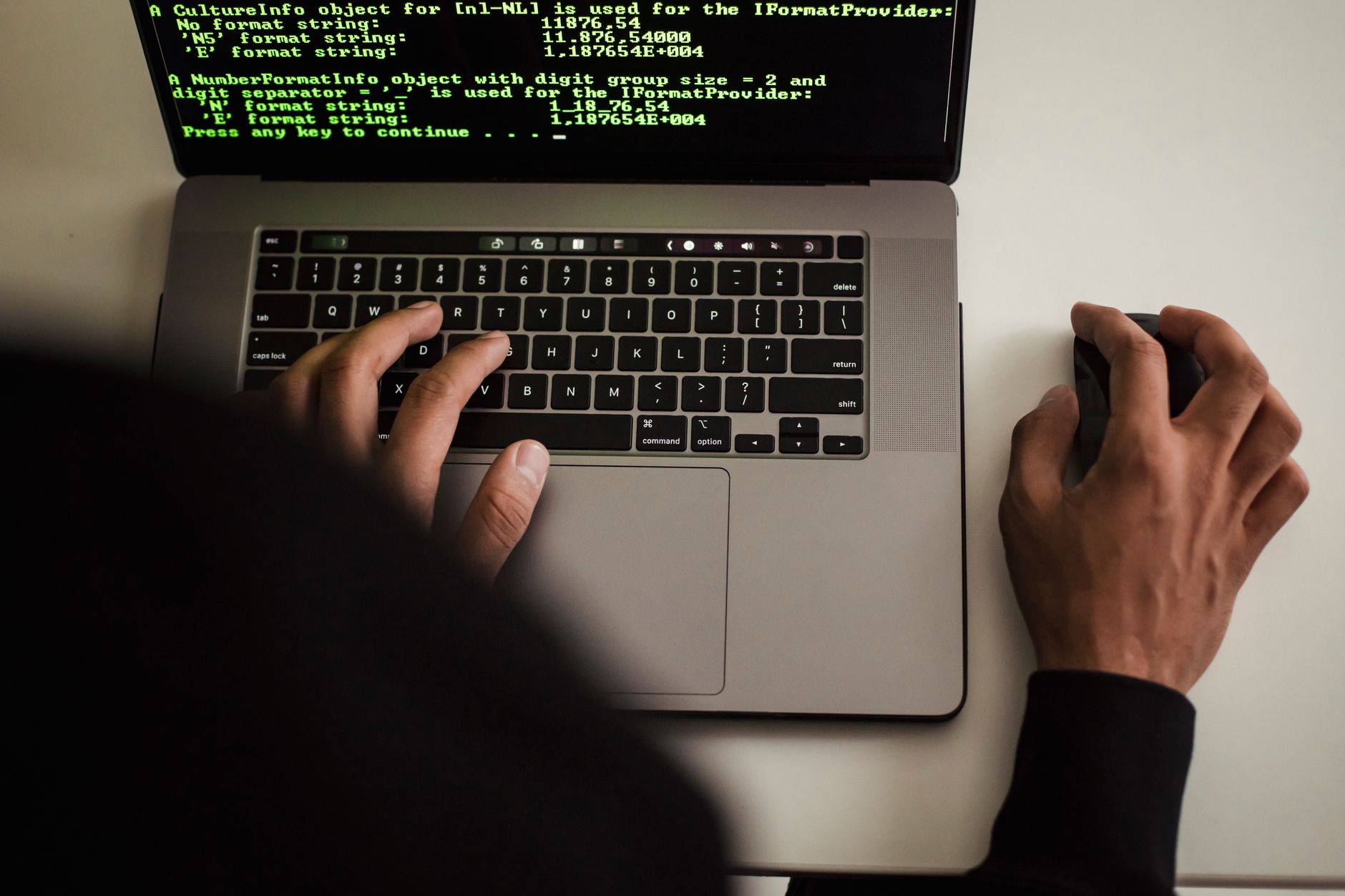 Programista w czarnej bluzie pisze kod na laptopie w biurze